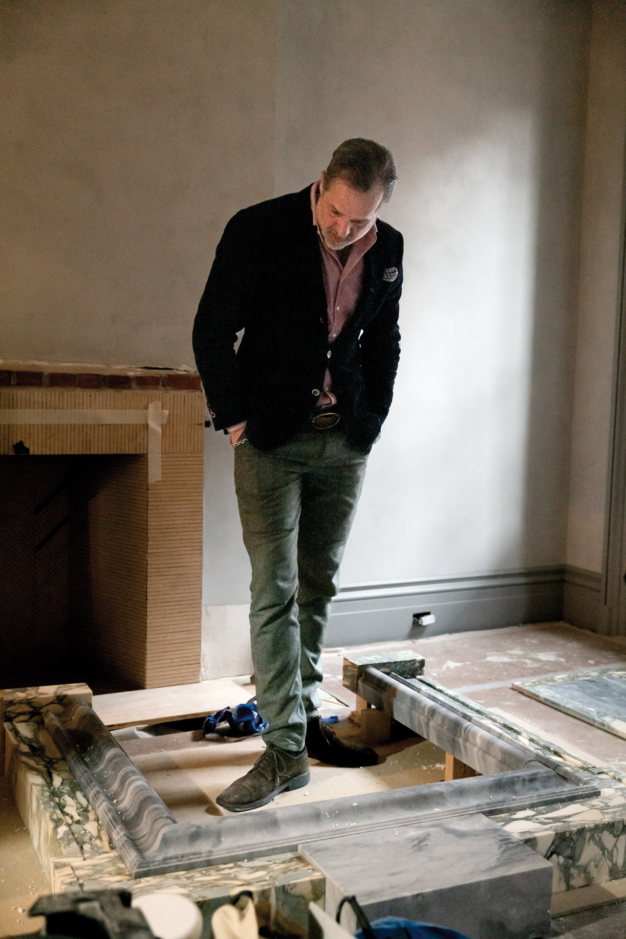 Steven inspects a mantelpiece of Breccia Verde Seravezza and Bardiglio Nuvolato he designed for his bedroom.